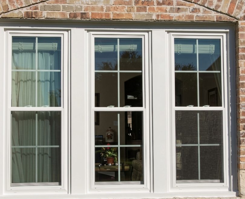 White-framed brick windows reflect how to know it is time for window replacement Plano, TX